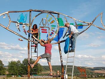 Mit Unterstützung von Bettina Schmidt und Wolfgang Will schuf der Berliner Künstler Herbert "Jimmy" Fell (mit Hut) eine neue Skulptur am "Dicken Turm" in Niederlauer. Foto: Manfred Mellenthin
