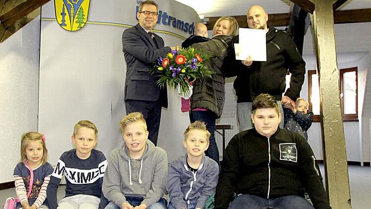 Der Bürgermeister der Gemeinde Weitramsdorf, Wolfgang Bauersachs (von links), übergibt die Urkunde des Bundespräsidenten Joachim Gauck und einen Blumenstrauß an Silke und Tino Kopp, die ihr siebtes Kind Adam im Arm hält. Zu sehen sind auch die übrigen Kinder (von links) Alina, Daniel, Raffael, Jonas, Adrian und Salin Kopp. Foto: Henrik Eckstein