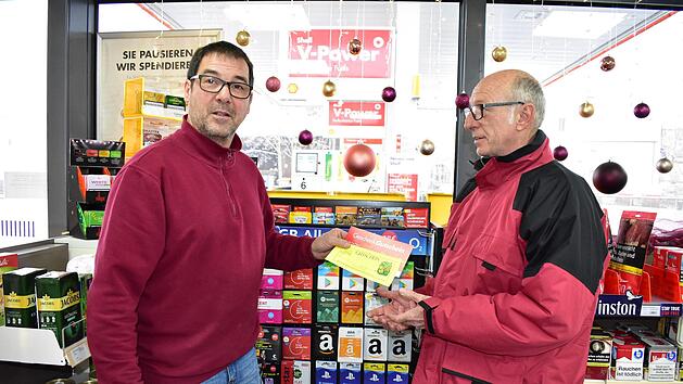 Klaus W&ouml;lfel, der Besitzer der Shell-Tankstelle in  Igensdorf, nimmt von seinem Kunden Gregor Mirsberger die zu Weihnachten  erhaltenen Gutscheine entgegen. Gutscheine sorgen in vielen regionalen Gesch&auml;ften f&uuml;r einen Boom nach Weihnachten. Foto: Petra Malbrich