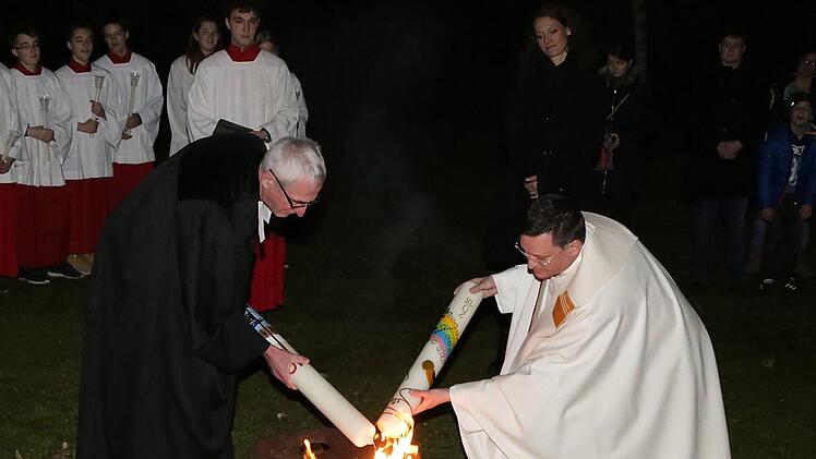 Ein bewegender Moment in der österlichen Lichtfeier, die die Obere Pfarre ökumenisch mit St. Stephan begeht: Pfarrer Matthias Bambynek und Pfarrer Walter Neunhoeffer entzünden am Osterfeuer die jeweilige Osterkerze.  Foto: Karl Zimmermann