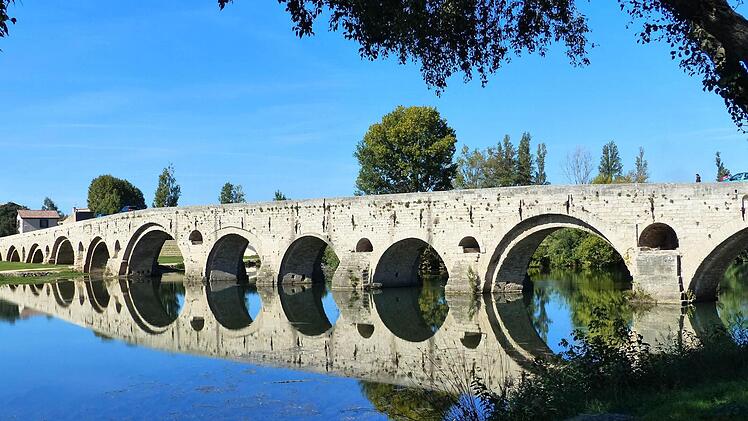 Zauberhaft: Der wolkenlose Himmel spiegelt eine malerische Brücke im Rhonekanal.
