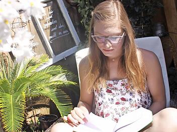 Marina Bräutigam genießt das Wetter auf der Terrasse. Um in der Berufsschule besser mitzukommen, hat sie sich ein spezielles Buch gekauft. Denn in der Realschule konnte sie noch keine tieferen Kenntnisse in Sachen Buchhaltung erlangen. Die wird sie aber bald brauchen.  Foto: Lisa Kieslinger