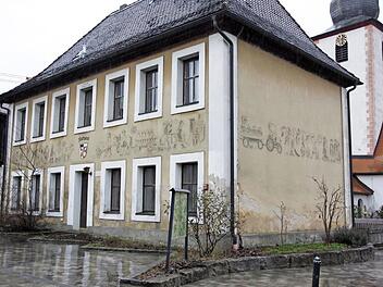 Das alte Rathaus in Affalterthal. In den Putz eingearbeitet sind Bilder aus dem Leben auf dem Land, mit dem Wappen der Gemeinde über dem Rathauseingang und mit der Inschrift darüber: "Erbaut 1784". Rechts daneben das wichtigste Haus im Dorf, die Kirche.  Foto: Reinhard Löwisch