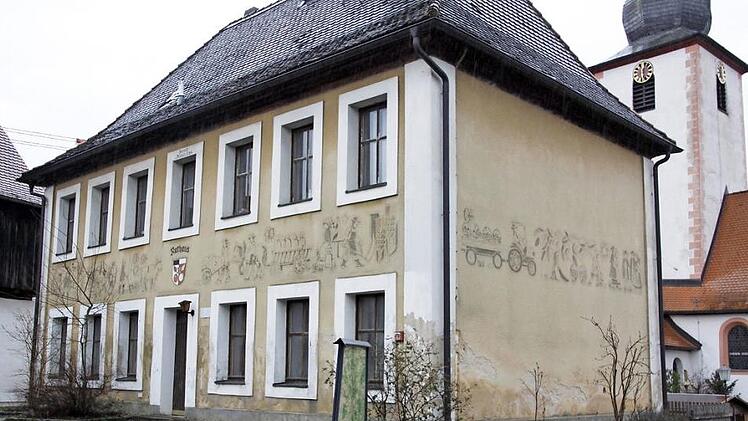 Das alte Rathaus in Affalterthal. In den Putz eingearbeitet sind Bilder aus dem Leben auf dem Land, mit dem Wappen der Gemeinde über dem Rathauseingang und mit der Inschrift darüber: "Erbaut 1784". Rechts daneben das wichtigste Haus im Dorf, die Kirche.  Foto: Reinhard Löwisch