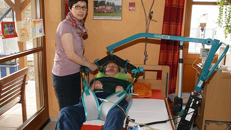 Fast eine Viertelstunde benötigt Monika Betz trotz Lift und Routine, um ihren Mann aus dem Rollstuhl ins Bett zu bringen. Nach zwei bis drei Stunden wird für den Wachkoma-Patienten das Sitzen zu anstrengend. Nicht nur zu liegen ist aber wichtig vor allem für die Lungenfunktion.  Foto: Sabine Weinbeer