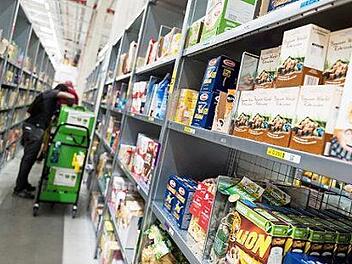 Ein Mitarbeiter von Amazon Fresh packt Waren in eine Transporttasche. Der Online-Handel mit Lebensmitteln boomt. Foto: Monika Skolimowska, dpa