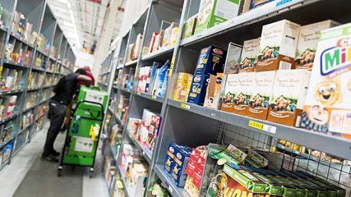Ein Mitarbeiter von Amazon Fresh packt Waren in eine Transporttasche. Der Online-Handel mit Lebensmitteln boomt. Foto: Monika Skolimowska, dpa