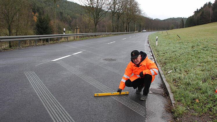 Jürgen Woll zeigt mit einer Wasserwaage, dass die Fräsrillen nicht tief sind. Foto: Friedwald Schedel